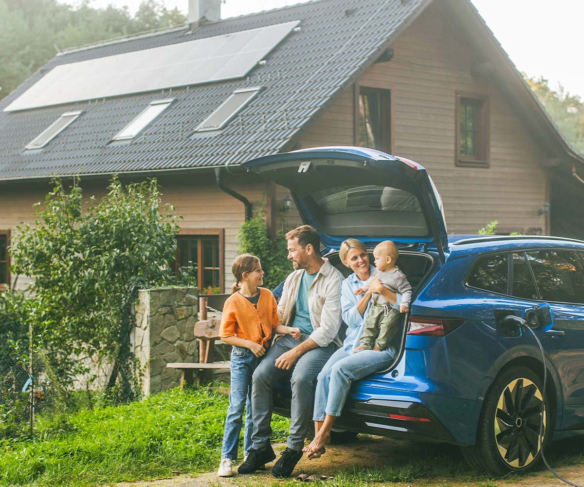 Familie mit Elektroauto vor einem Haus mit Photovoltaikanlage